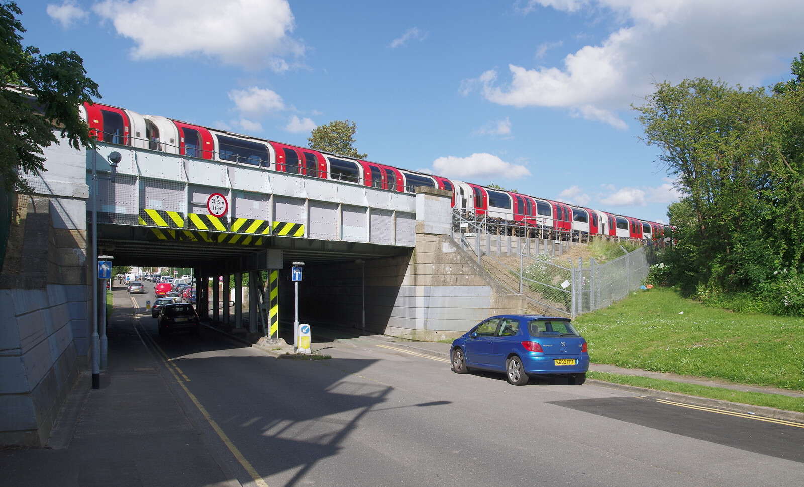 Ein Fahrzeug der Marke Peugeot �berquert eine Br�cke �ber die Bridgwater Road in Ruislip. Die Aufnahme entstand am 10. Juni 2014 und zeigt einen Zug der Londoner U-Bahn, Central Line, Baureihe 1992, von der Seite.