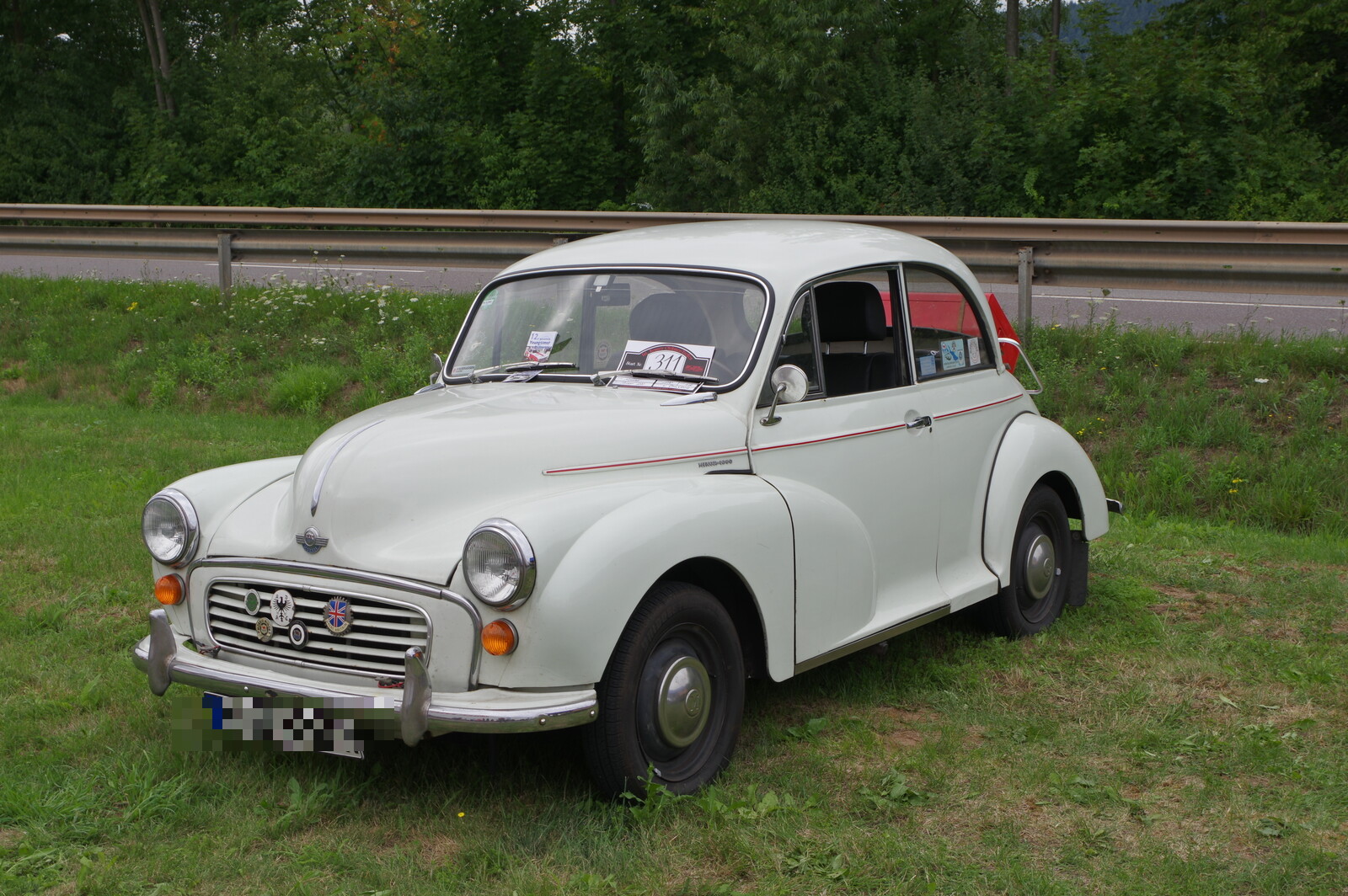 Ein wei�er Morris Minor 1000 von 1970 steht bei einer Oldtimer-Ausfahrt am Stra�enrand, schr�g von vorn zu sehen. Die Aufnahme stammt vom 16. Juli 2017.