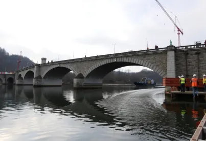 Steinerne Bogenbrücke von 1847 während Bauarbeiten über ruhigem Fluss im Tal