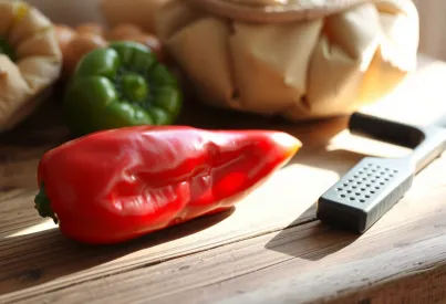 Stilleben mit roter Paprika und antikem Messer auf Holztisch in Landhausküche