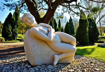 Steinskulptur im Park in der Toskana: Menschliche Figur in nachdenklicher Haltung aus Kalkstein