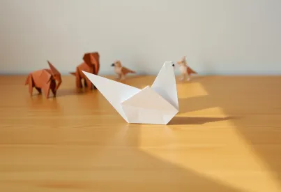 Fotografie eines Origami-Kranichs auf Holztisch mit dynamischer Licht- und Schattenwirkung