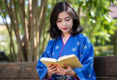 Frau in Kimono liest im Park von Kyoto unter Morgensonne