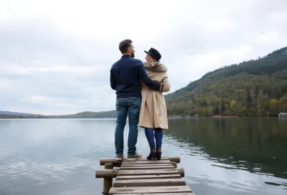 Paar auf Holzsteg an einem ruhigen See im frühen Herbst