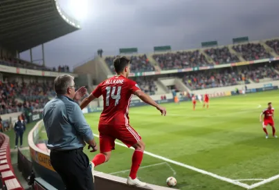 Spielsituation in einem kleinen Stadion bei Marseille: Spieler in rot-weißem Trikot spielt präzisen Pass