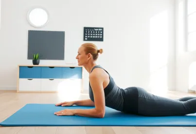 Frau in seitlicher Plank-Position auf Pilatesmatte in lichtdurchflutetem Raum