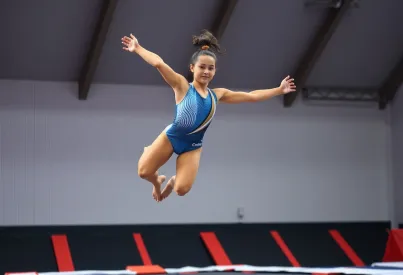 Trampolinübung einer jungen Athletin in Berliner Sporthalle: Präzision und Eleganz in der Luft