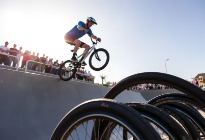BMX-Fahrer vollendet Sprung über hölzerne Rampe im Skatepark