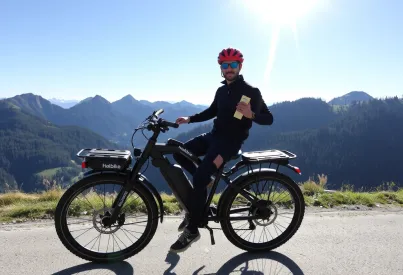 Mann auf E-Bike der Marke Haibike pausiert auf Schotterweg in den bayerischen Alpen