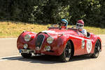 Ein roter Jaguar XK 120 f�hrt beim Solitude Revival 2022 auf einer Rennstrecke; das Fahrzeug ist schr�g von vorn mit zwei Insassen zu sehen. Die Aufnahme stammt vom 17. Juli 2022.