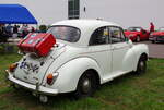 Ein wei�er Morris Minor 1000 von 1970 steht bei einem Autotreffen, schr�g von hinten aufgenommen.
