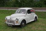Ein wei�er Morris Minor 1000 von 1970 steht bei einer Oldtimer-Ausfahrt am Stra�enrand, schr�g von vorn zu sehen.