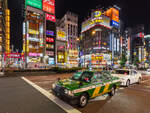 Ein gr�n-gelbes Toyota Crown Comfort Taxi f�hrt nachts auf der Yasukuni-dori Avenue in Kabukich?, Shinjuku, Tokio, vor farbenfrohen Leuchtreklamen.